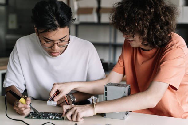 Two secondary school students working together on an electronics circuit board in a classroom lab